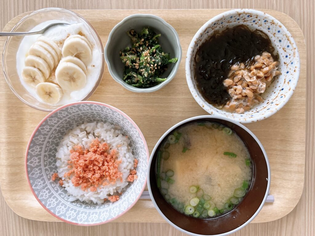 もち麦ごはん90g、鮭フレーク、味噌汁、納豆ともずく酢、ほうれん草のごま和え、ヨーグルトと果物の朝ごはん写真